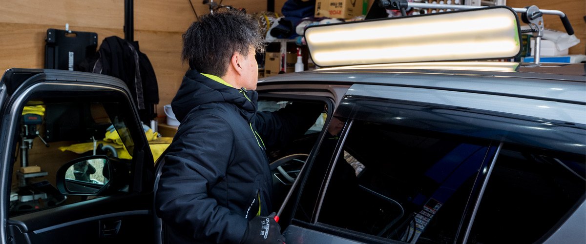 車のへこみを確かめる職人